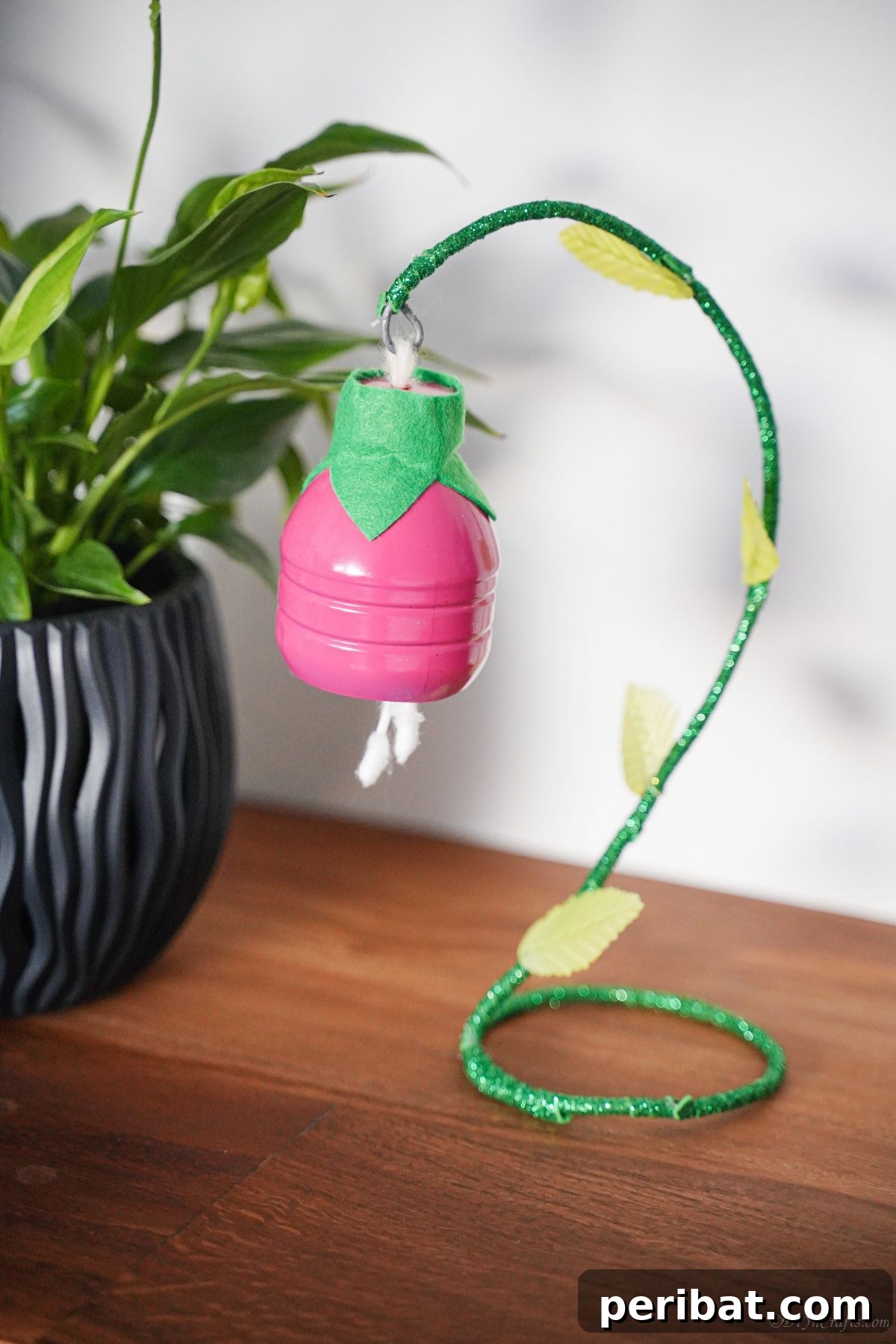 Upcycled Plastic Bottle Blossoms 2 Pink hanging plastic bottle flower decoration on a rustic wooden table