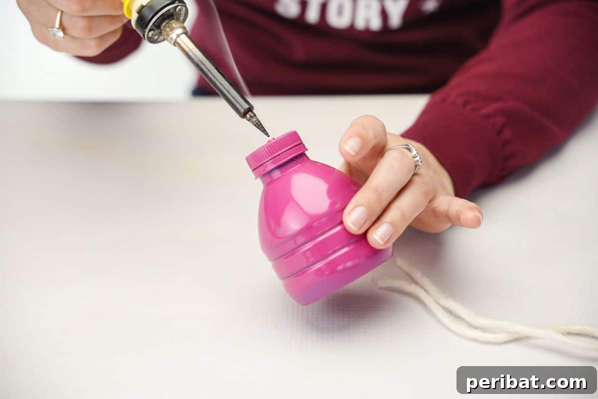 Upcycled Plastic Bottle Blossoms 10 Soldering iron creating a hole in the lid of a pink plastic bottle