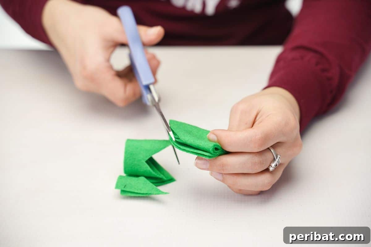 Upcycled Plastic Bottle Blossoms 12 Blue scissors cutting green felt into a 'V' shape
