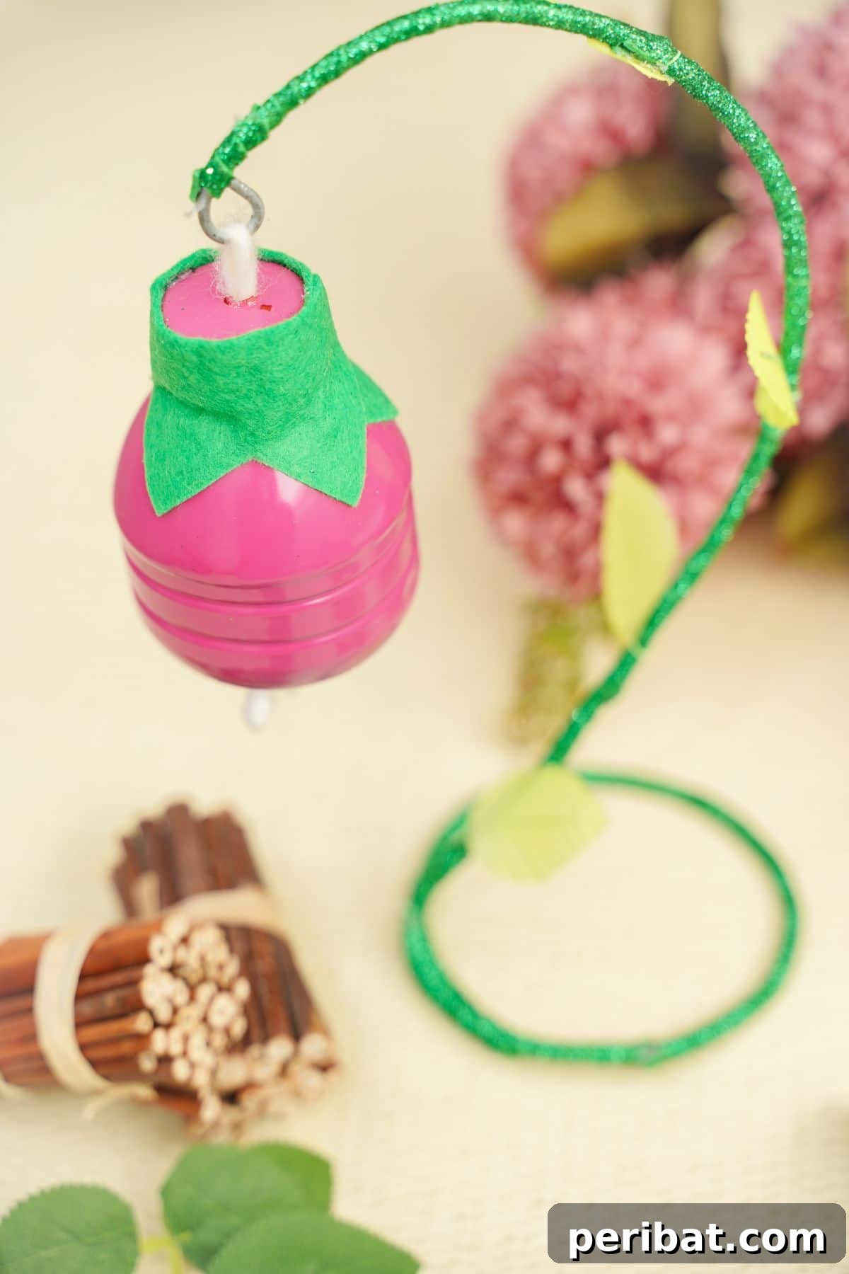 Upcycled Plastic Bottle Blossoms 16 Pink plastic bottle flower on a green stem placed next to cinnamon sticks