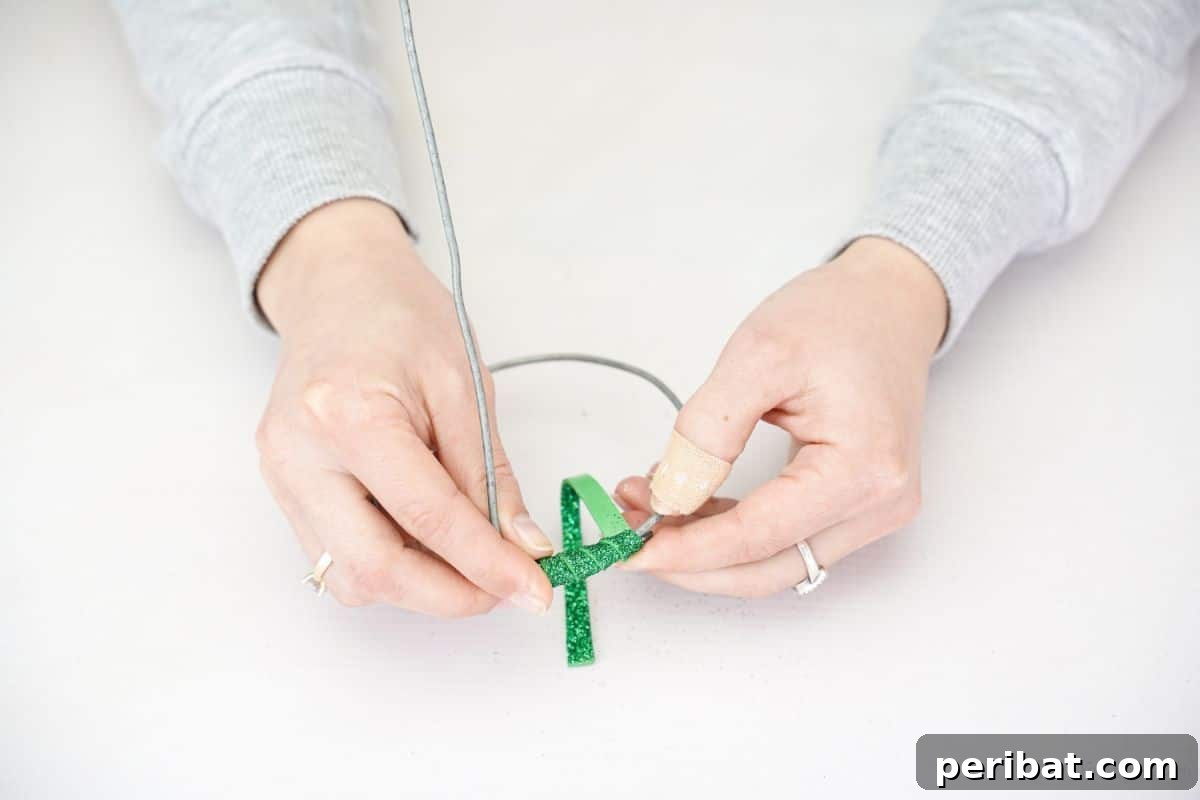 Upcycled Plastic Bottle Blossoms 7 Craftsperson wrapping a wire flower stem with green glitter foam paper