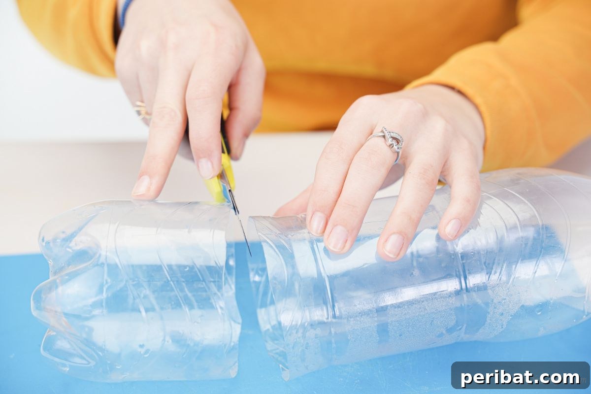 An empty plastic bottle on a blue mat being cut in half with a craft knife.