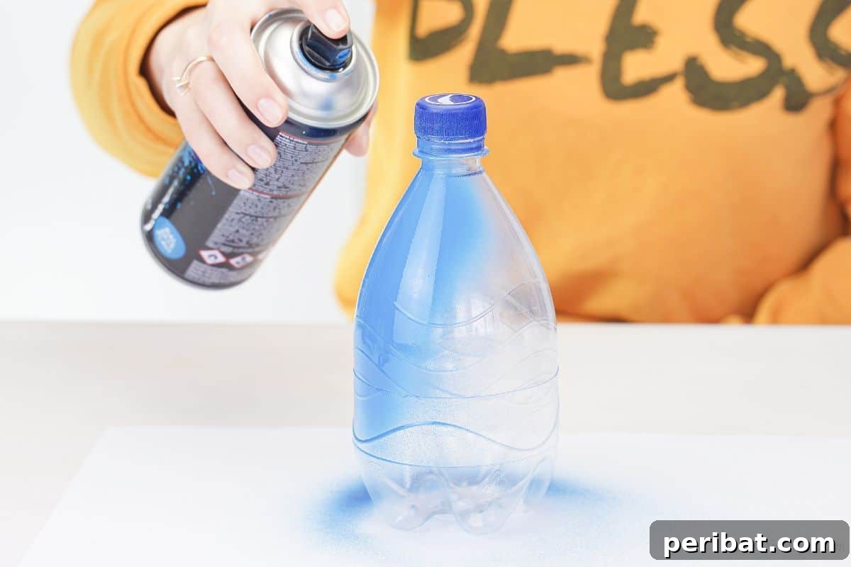 A person in orange clothes spraying a plastic bottle blue with paint.