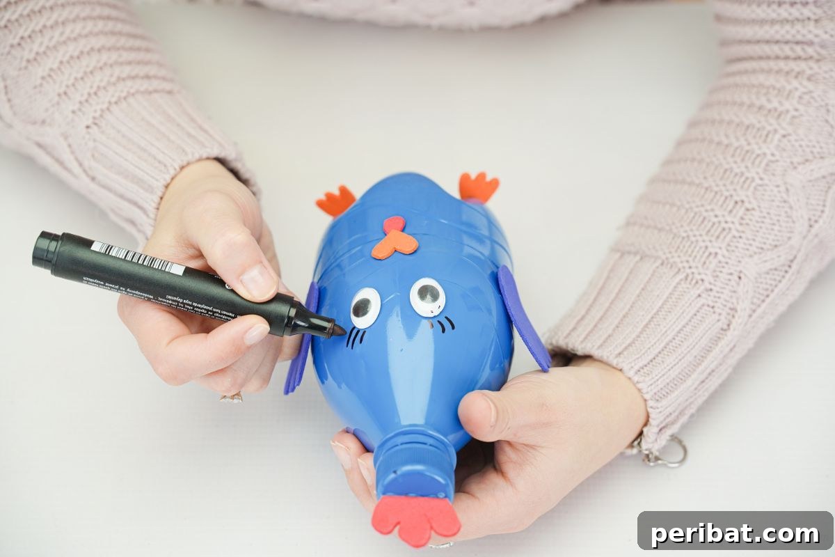 A hand using a black marker to draw eyelashes on the turkey craft.