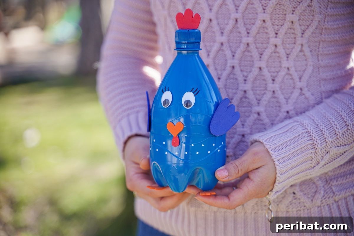 A woman in a pink sweater proudly holding her finished blue plastic bottle bird craft.