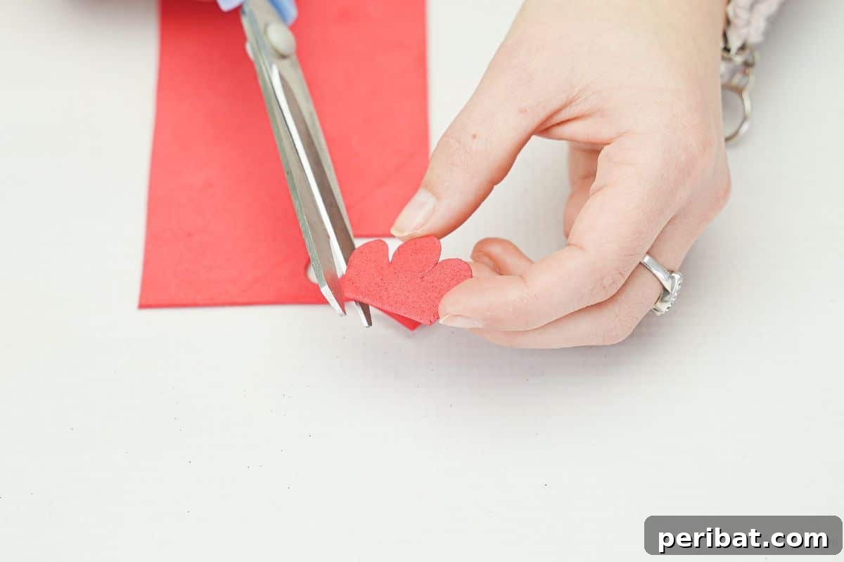 Gray scissors cutting a red foam paper wattle for the turkey craft.