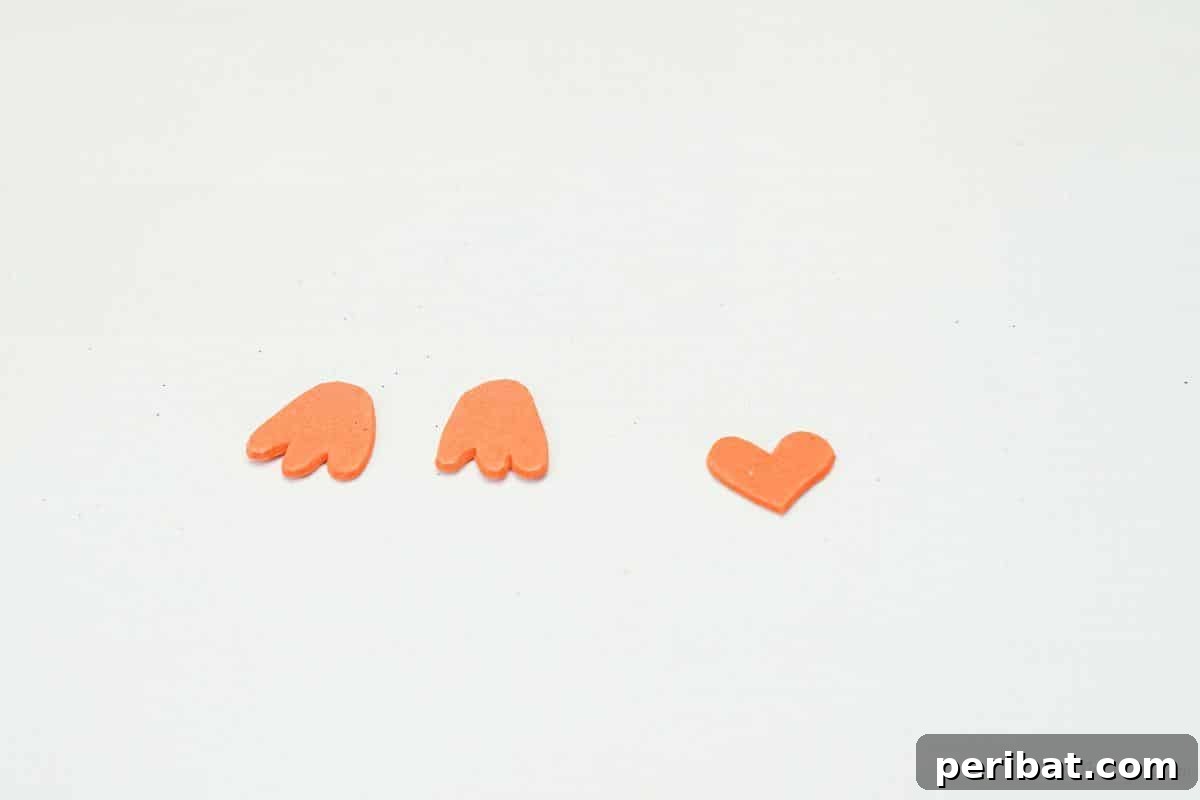 Orange foam feet and a heart shape for the beak on a white table.