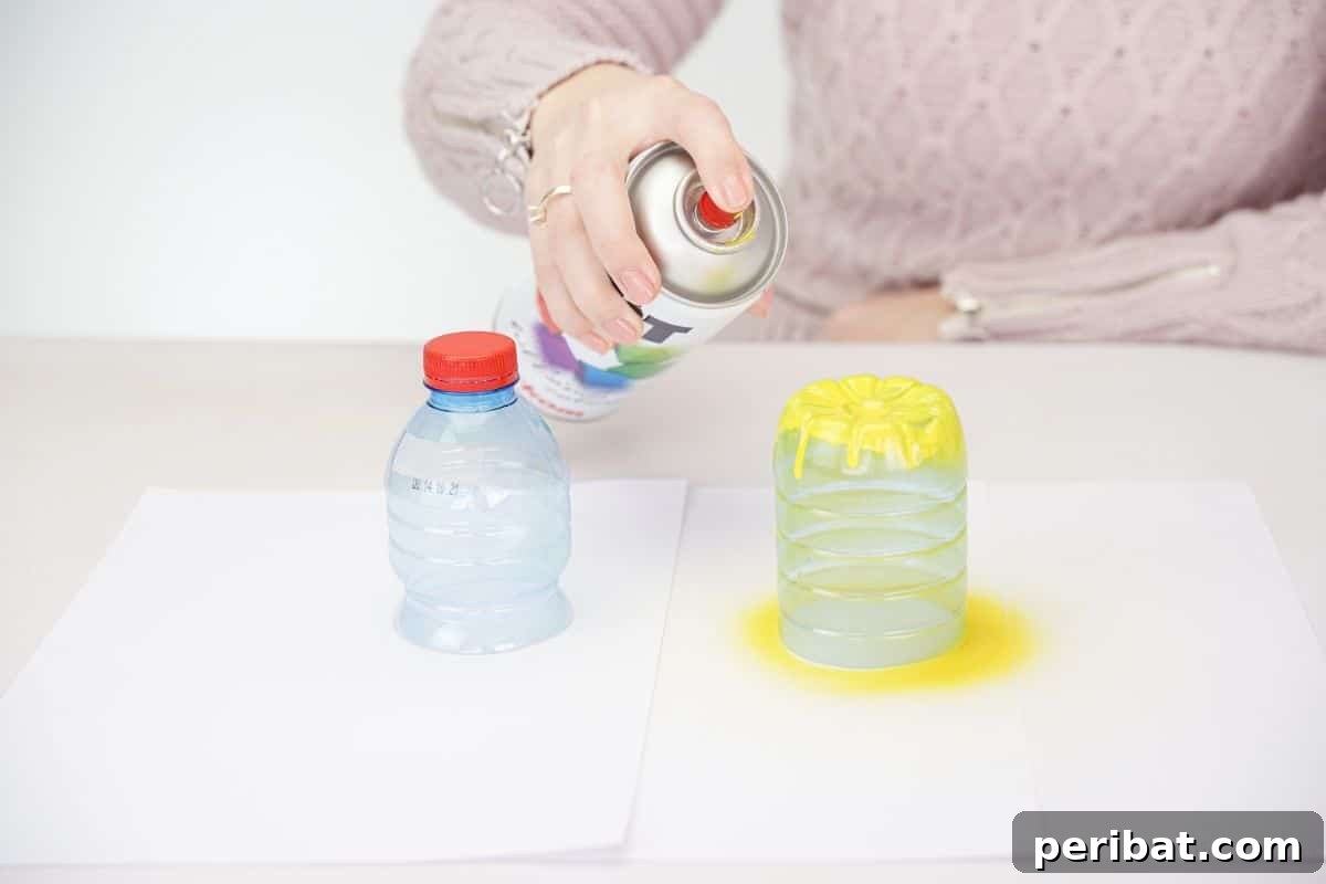 A hand holding a yellow spray paint can above plastic bottle pieces resting on white paper.