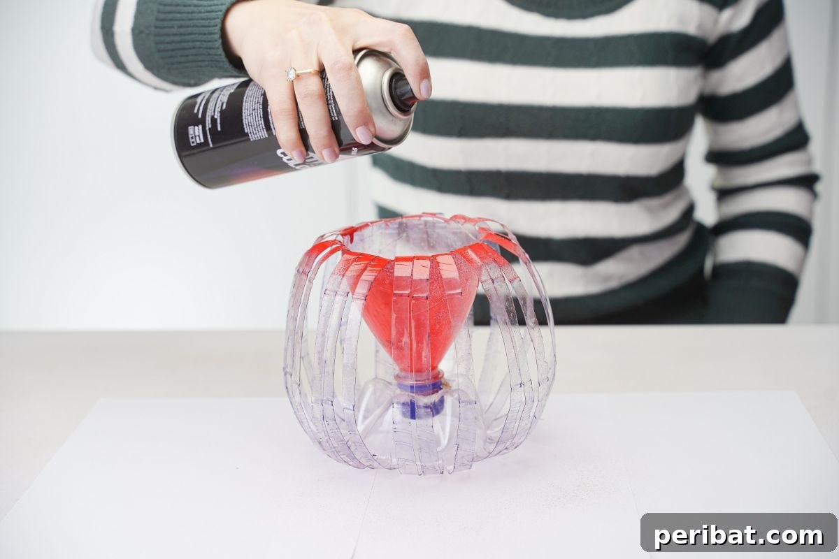 Stylish Recycled Bottle Planters 7 hand holding red spray paint above plastic globe