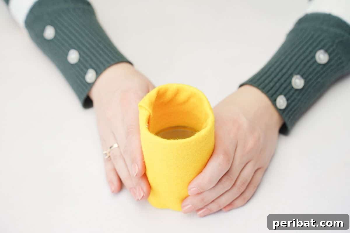 Hands wrapping yellow felt around a plastic bottle base