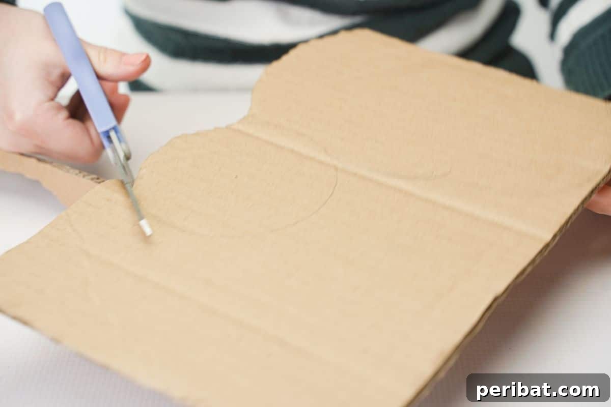 Light blue scissors cutting a cardboard piece for the caterpillar's head and body