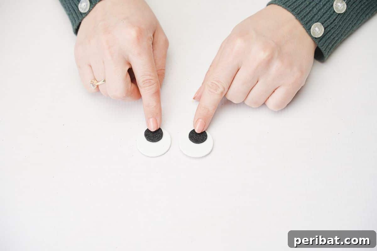 Black and white foam eyes being held down by fingers