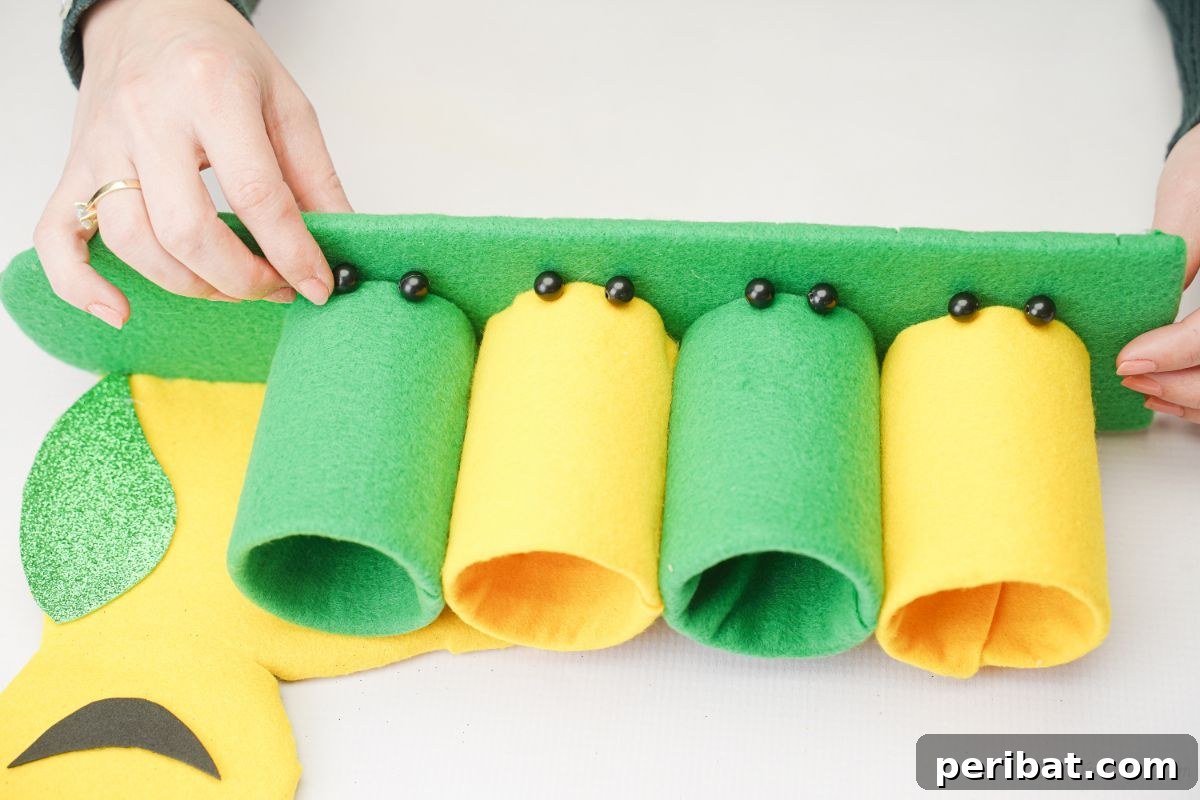 Black beads being glued to the front of the caterpillar pencil holder as feet