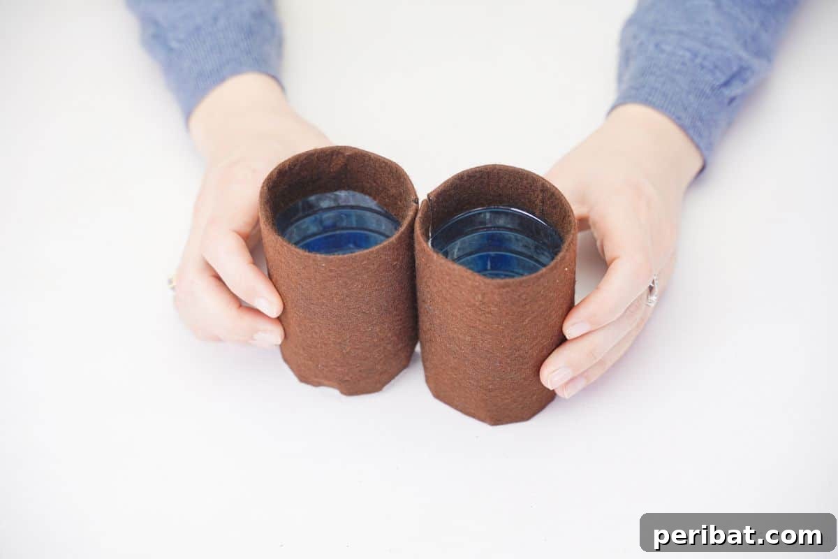 Hands holding two brown foam-covered plastic bottle sections, showcasing the neat covering technique.