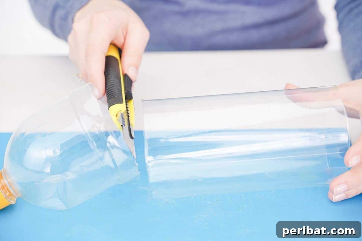 A hand using a yellow and black craft knife to cut the top off a clear plastic bottle.