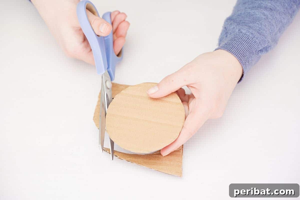 Blue scissors cutting a circular shape from a piece of cardboard.