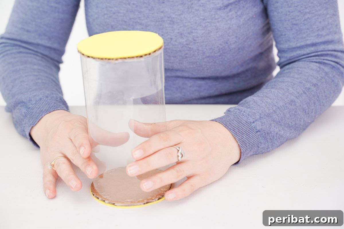 A yellow-covered cardboard circle glued to one end of a plastic bottle body, forming the car's front or back.