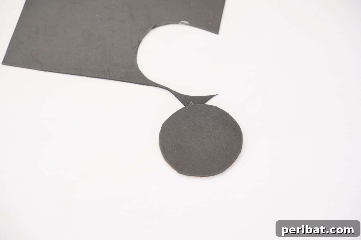 A neatly cut black foam circle glued onto a cardboard base, ready to be a car wheel.