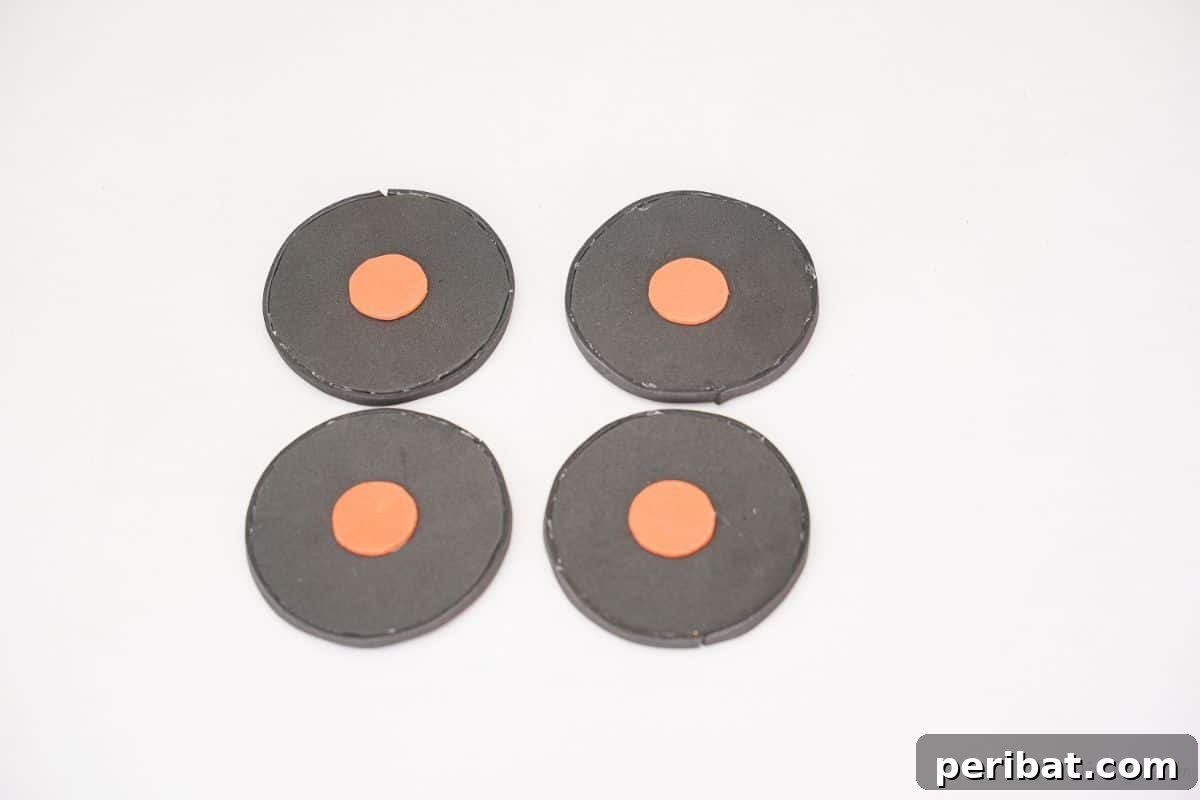 Four black foam car wheels, each with a small orange foam circle glued in the center as a hubcap.