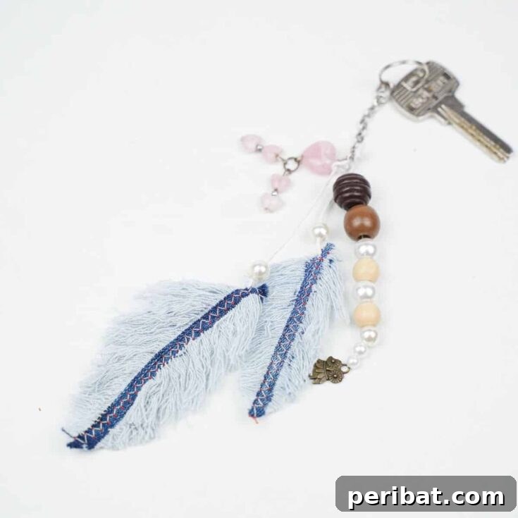 beaded keychain with old blue jeans feathers on bottom laying on white table