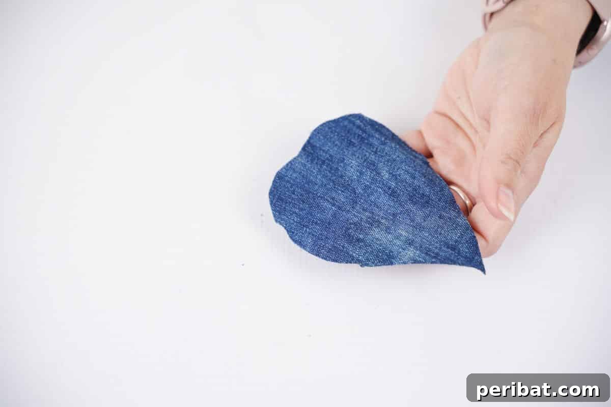 Handmade Denim Feather Keychain 3 hand holding teardrop shape piece of denim