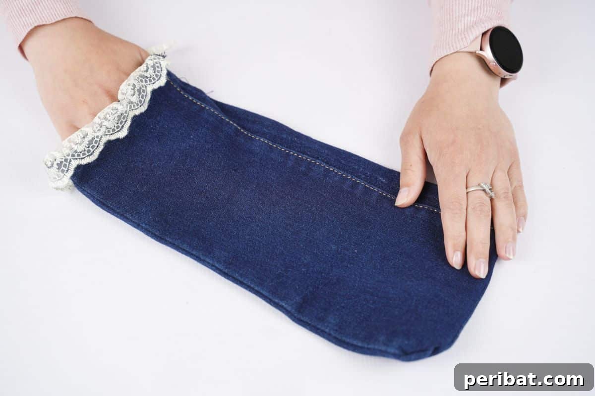 Rustic Denim Wine Cozy 4 Hand turning the denim wine bottle cover right side out, showcasing the lace edge.