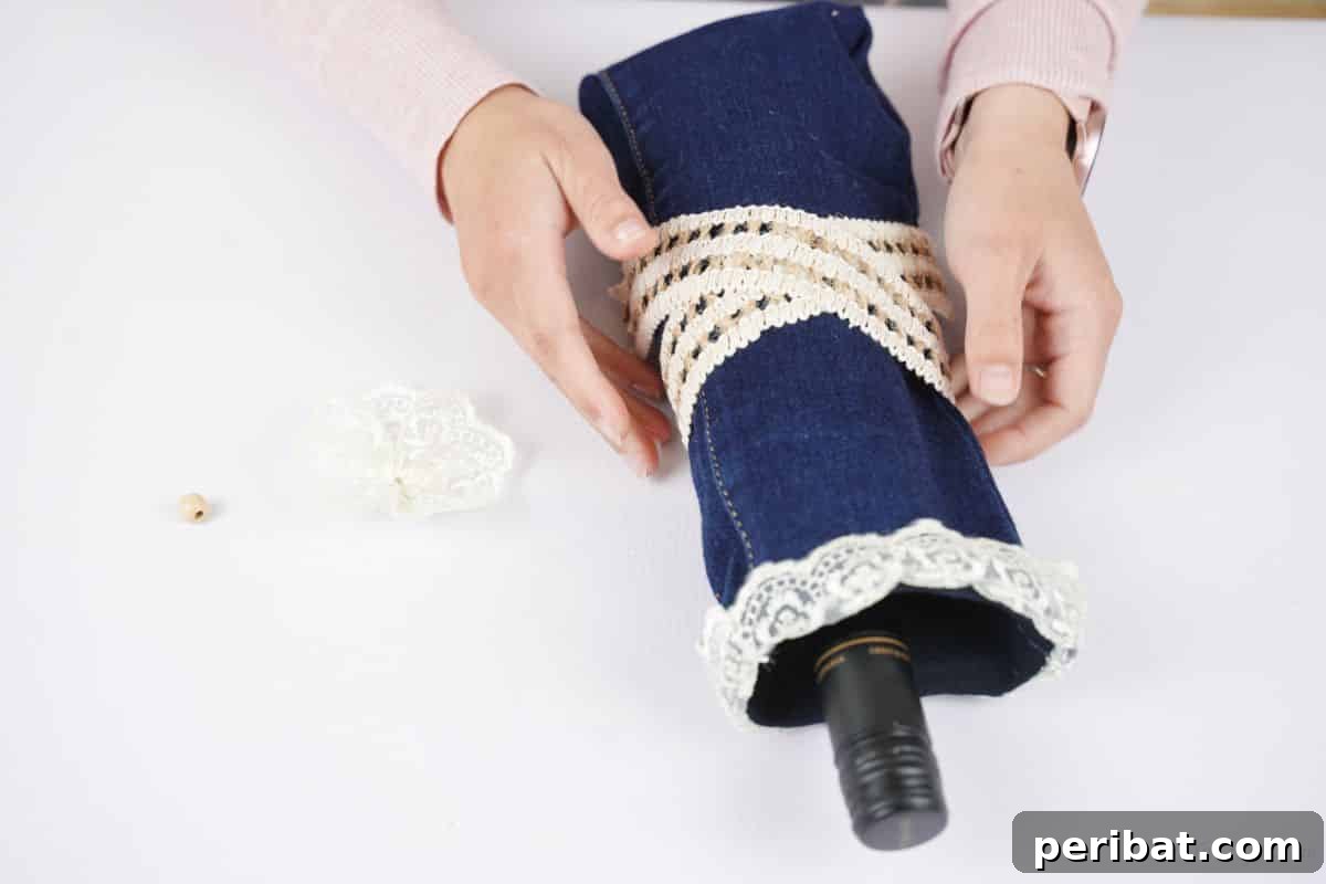 Rustic Denim Wine Cozy 5 Hands holding and gluing a lace ribbon around the middle of the denim wine bottle cover to create a cinch.