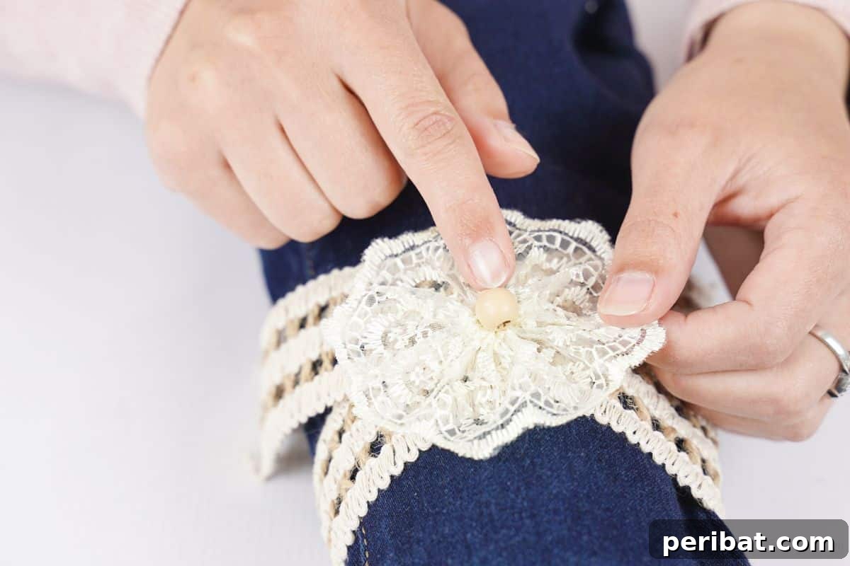 Rustic Denim Wine Cozy 6 Hand holding a lace circle being glued onto the burlap ribbon on the wine bottle cover.