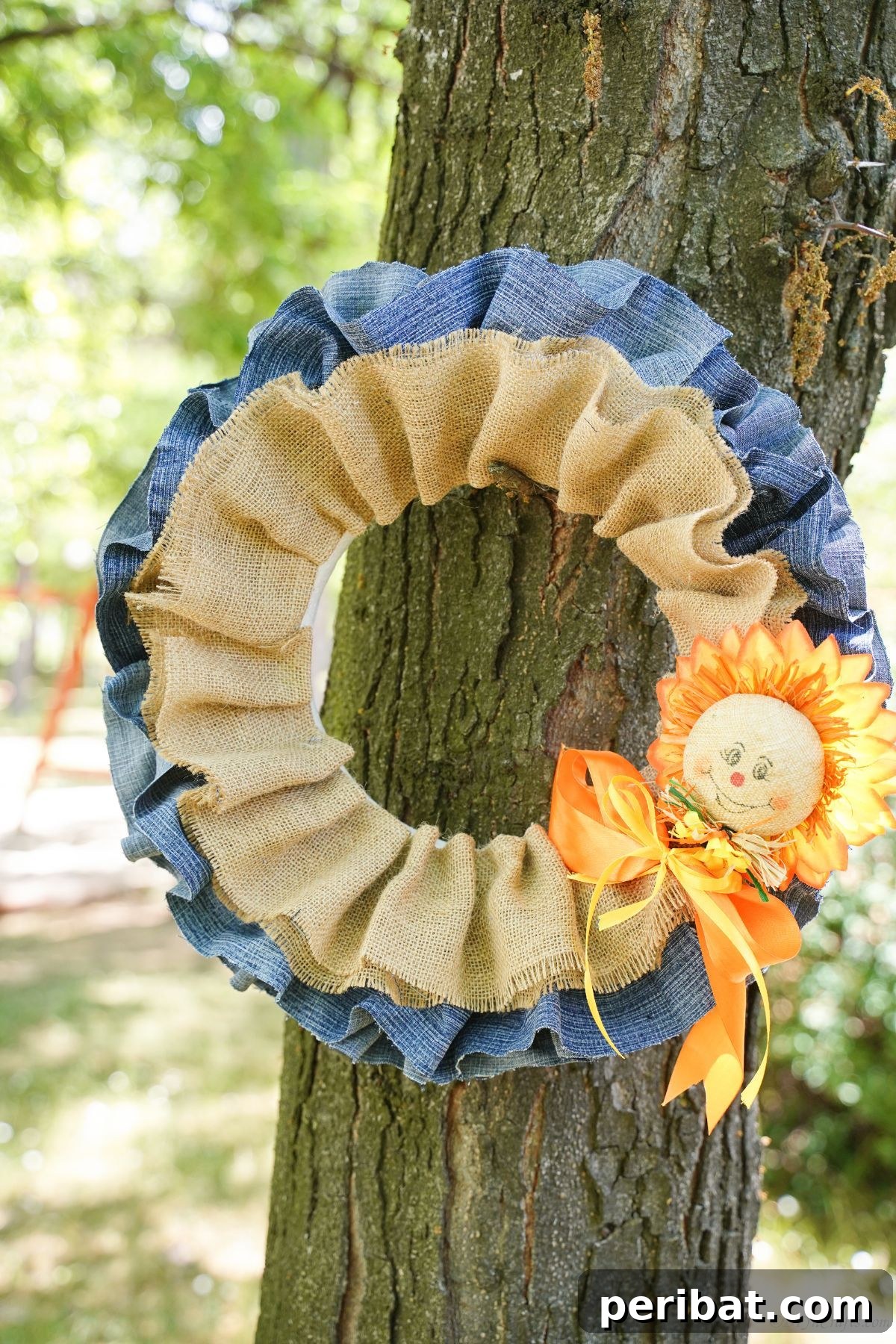 Autumn's Embrace Denim and Burlap Door Wreath 3 Close-up of a handmade fall denim and burlap wreath adorned with a small scarecrow and ribbon.