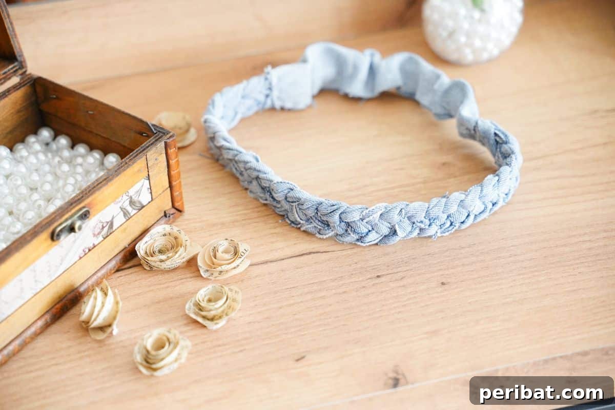 Denim Reimagined: Braided Headband DIY 16 Finished braided denim headband on a table next to paper flowers