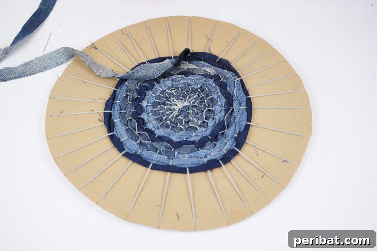 Gray yarn being carefully wrapped and tied around the center of a cardboard circle, creating the warp threads of the loom.
