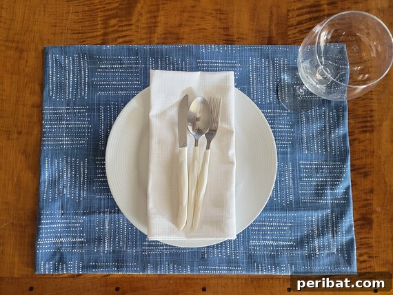 A completed woven denim placemat, showcasing its rustic beauty on a gray dining table with a potted plant.
