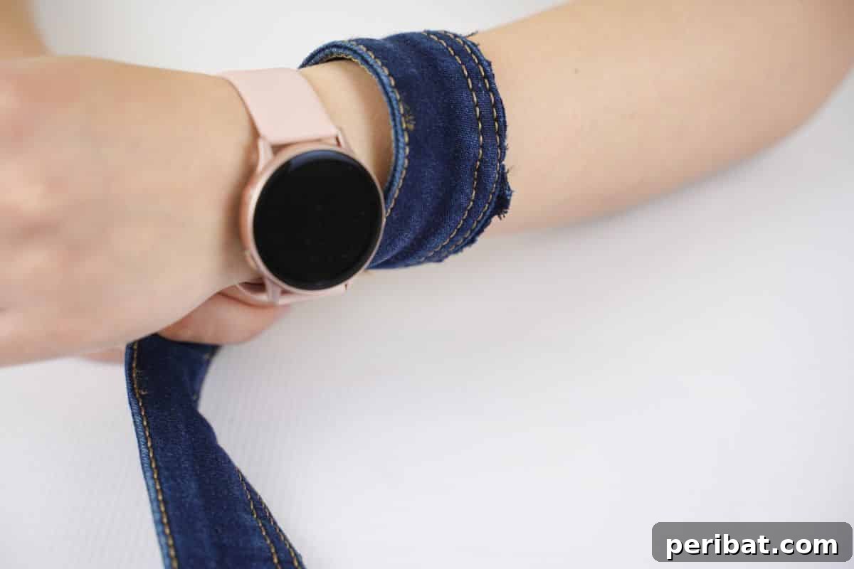 Denim Reborn Wristwear 3 Close-up of a finished denim cuff wristband with bead embellishments on a person's wrist
