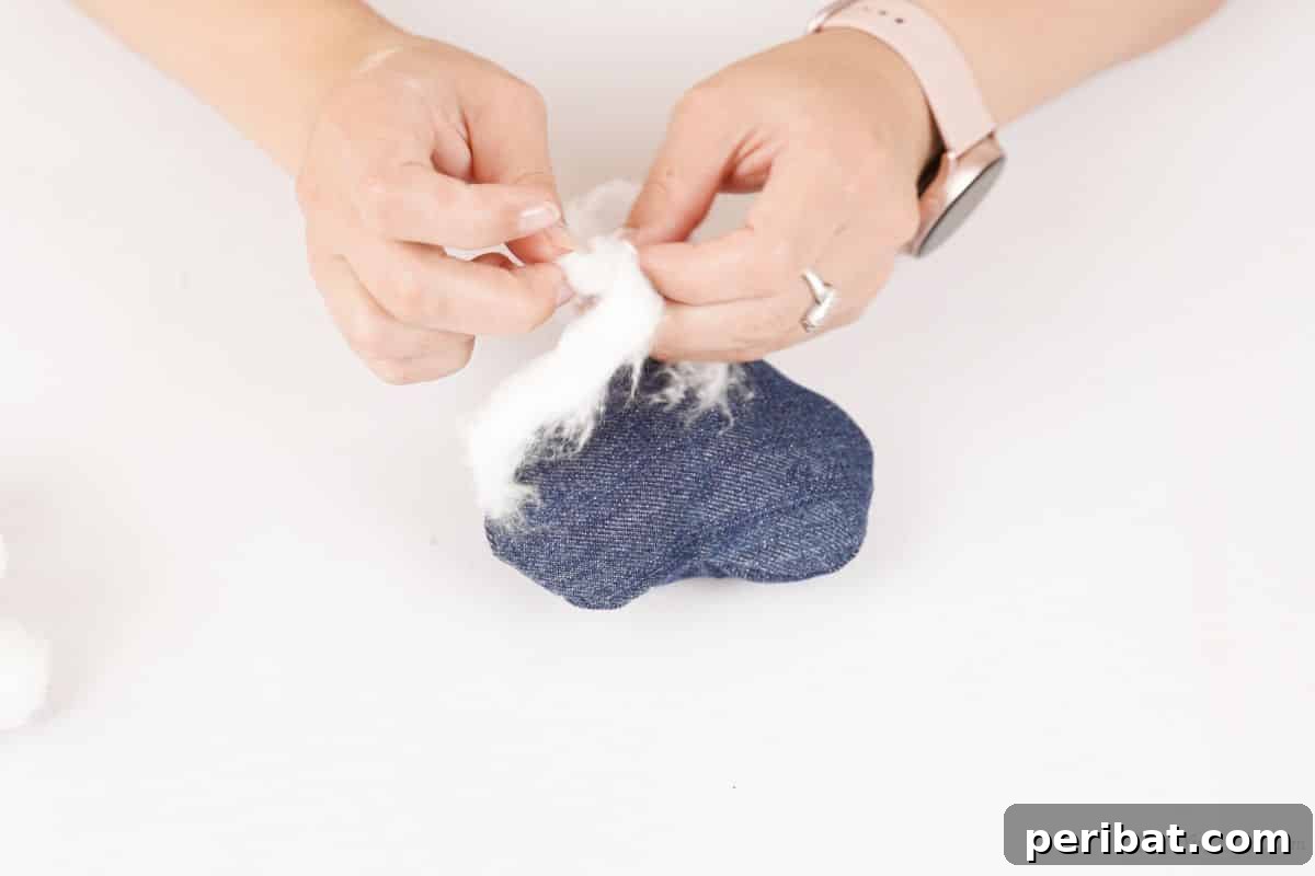 hands stuffing cotton inside small denim heart