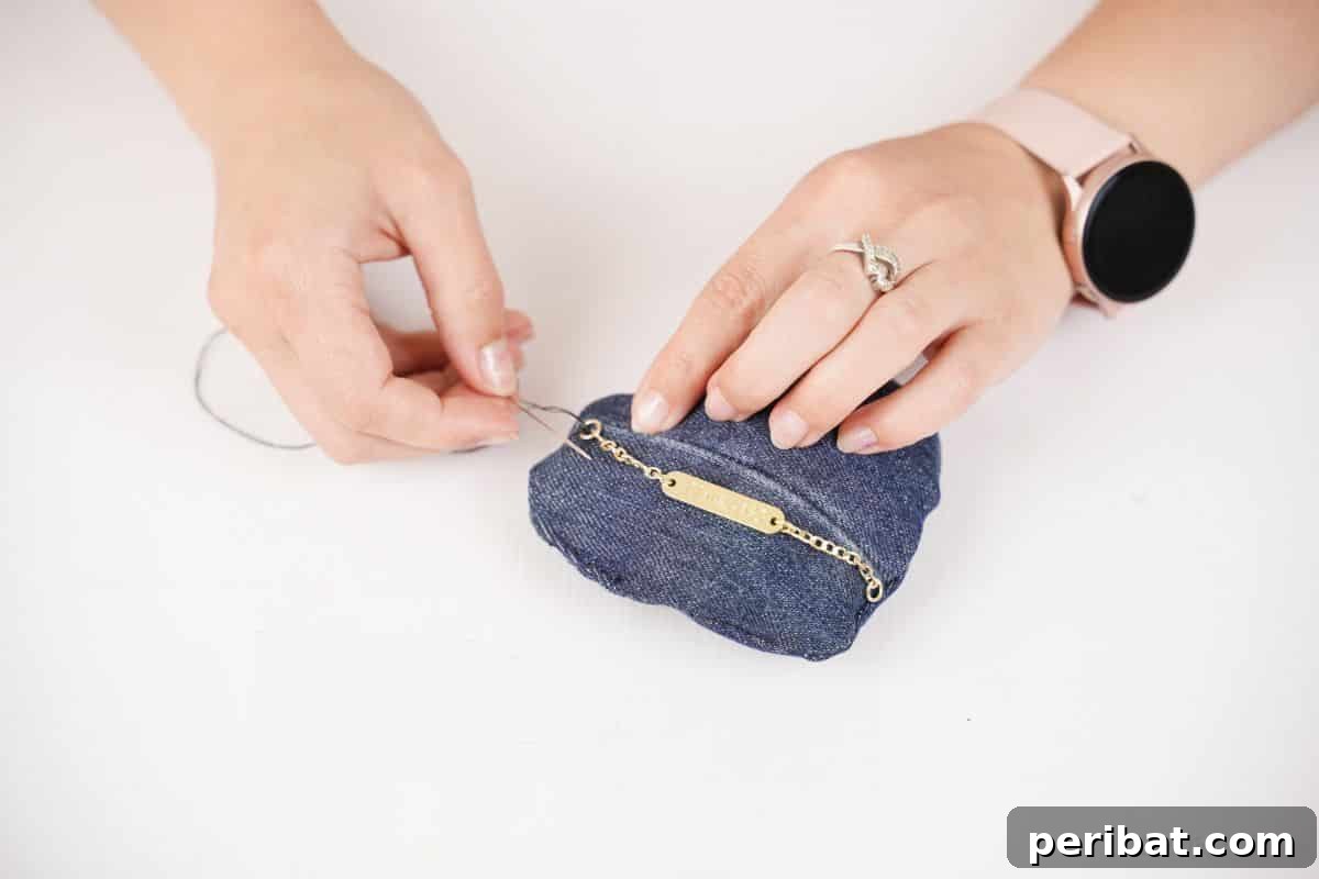 gold chain being sewn onto denim heart
