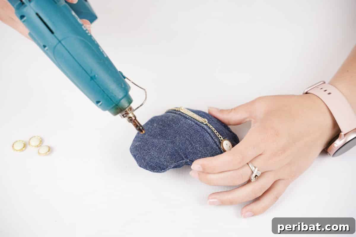 blueglue gun adding button onto denim heart