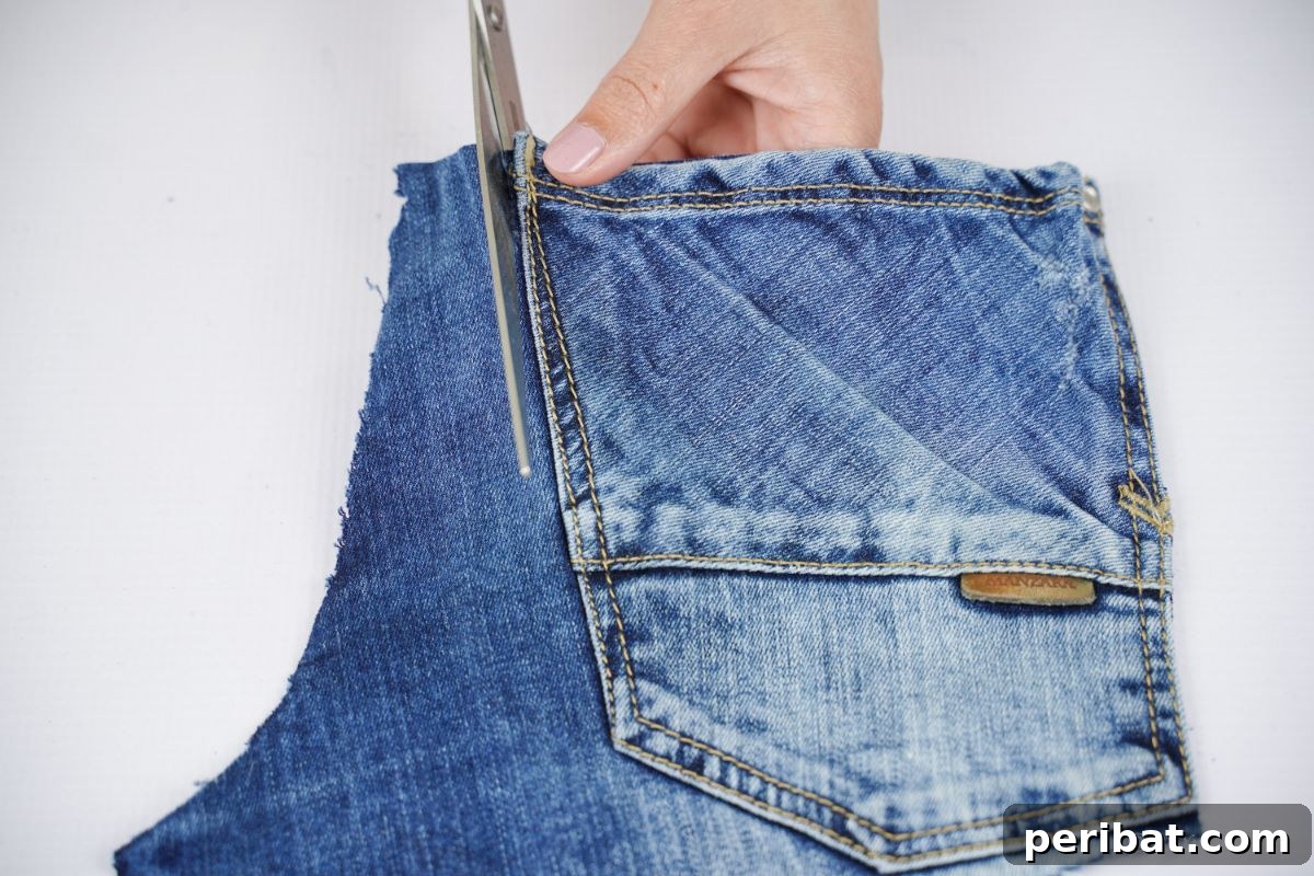 Craft a Stylish Denim Book Cover with Pockets 12 Scissors meticulously cutting a back pocket from a pair of denim pants.