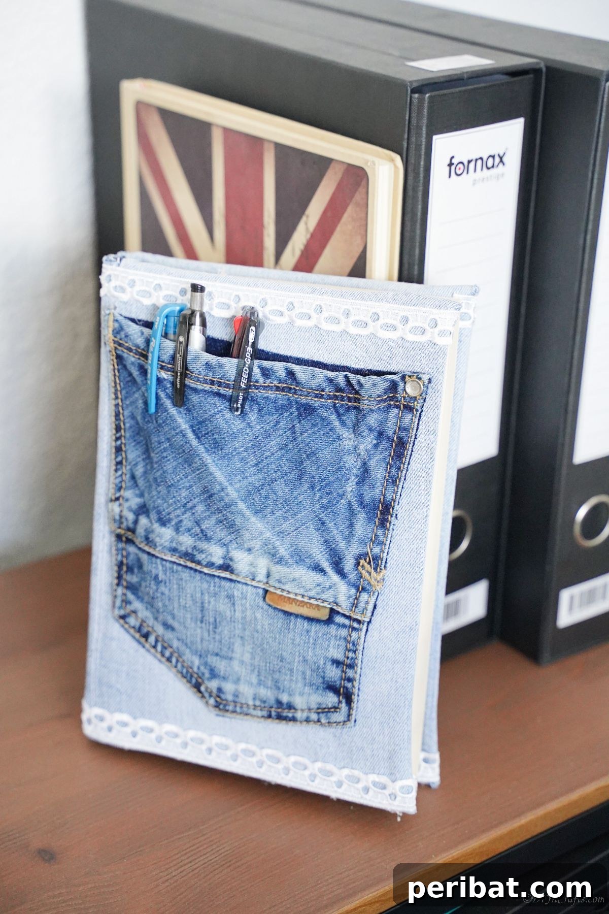 Craft a Stylish Denim Book Cover with Pockets 14 Fully assembled denim pocket book cover with pens neatly stored in its pocket, displayed on a shelf.