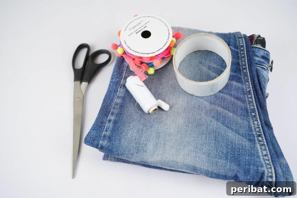 folded blue jeans on white table with scissors needle and thread