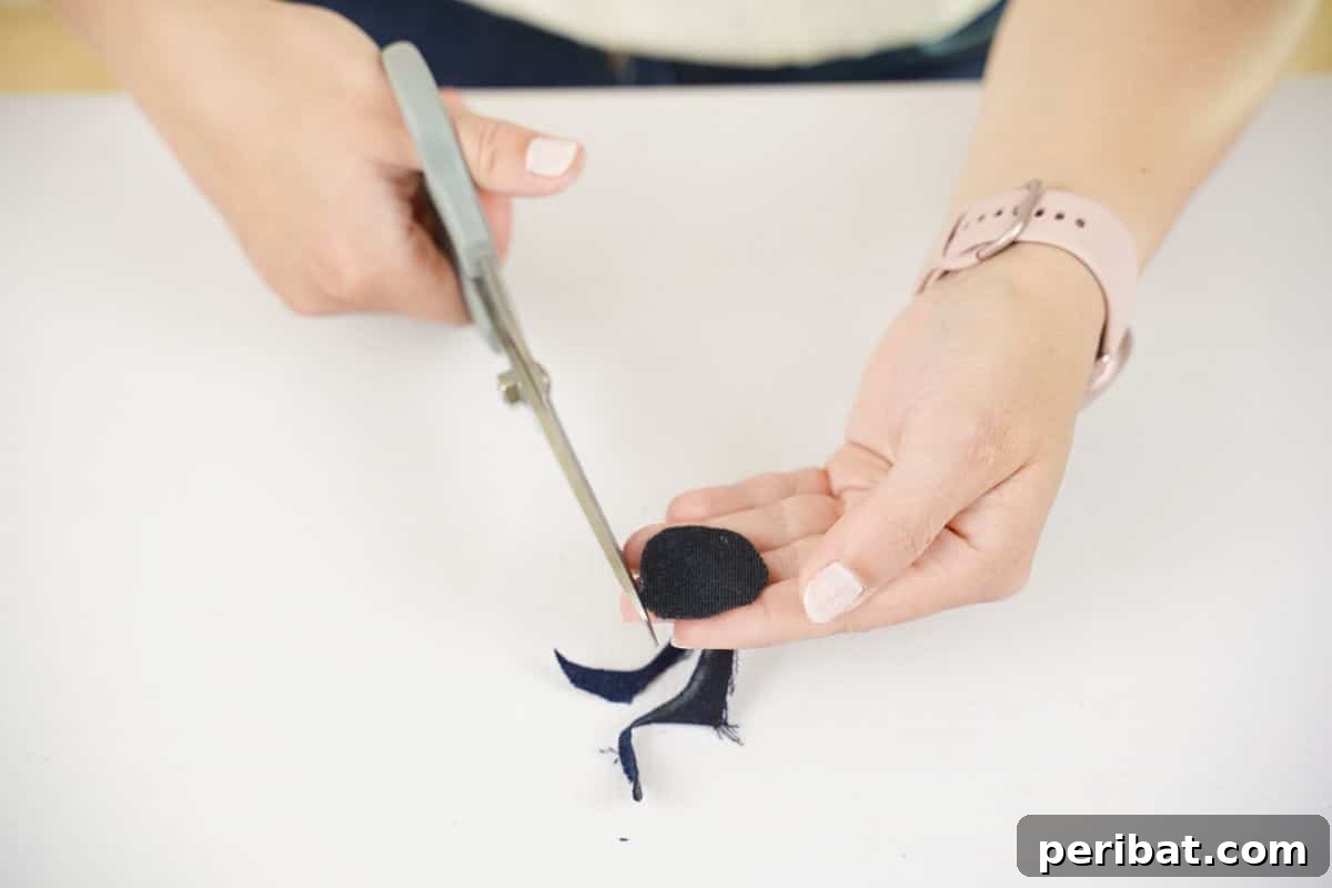 hand holding small denim circle with scissors