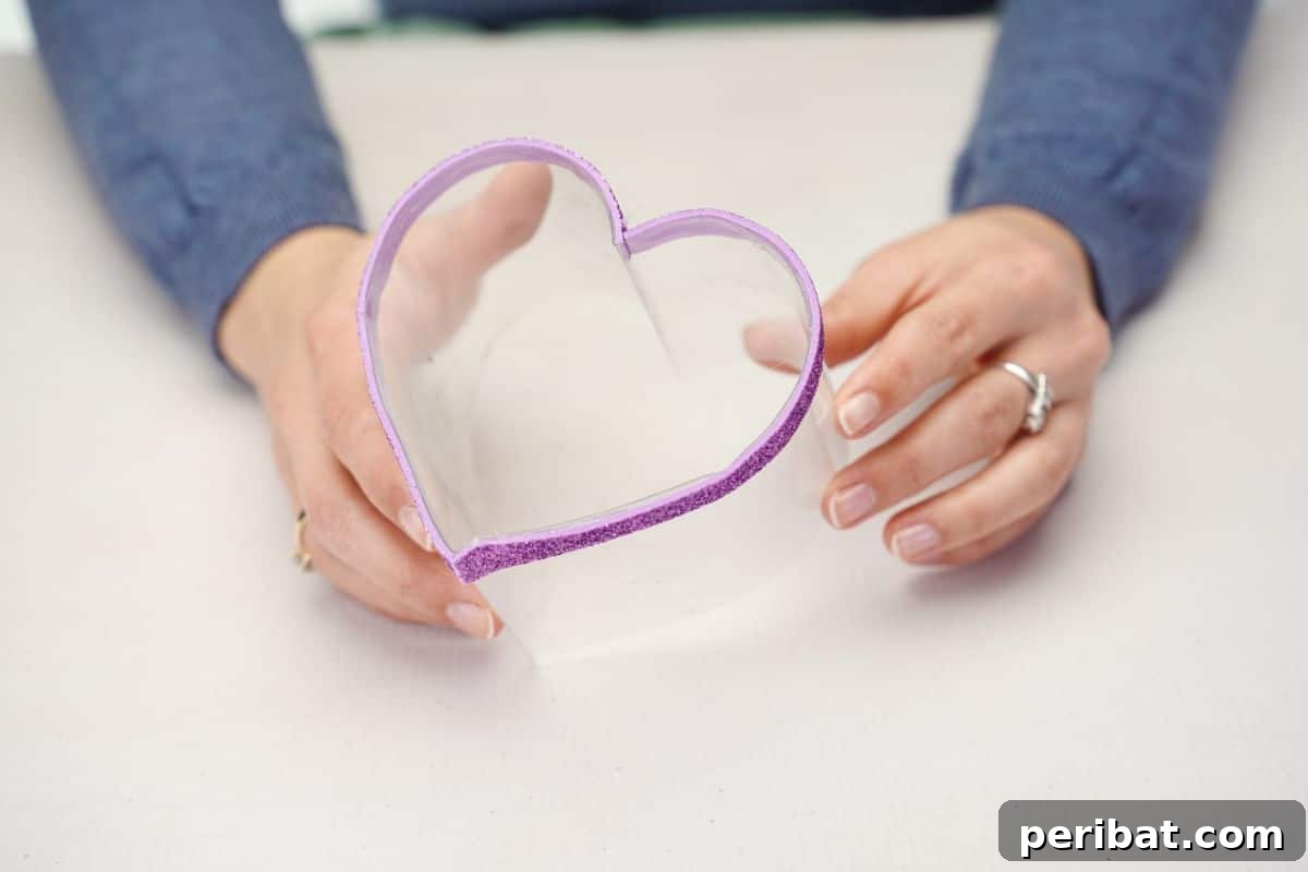 From Bottle to Heart: Upcycled Gift Box Craft 6 Purple glitter strip being glued around the base of a plastic heart box.