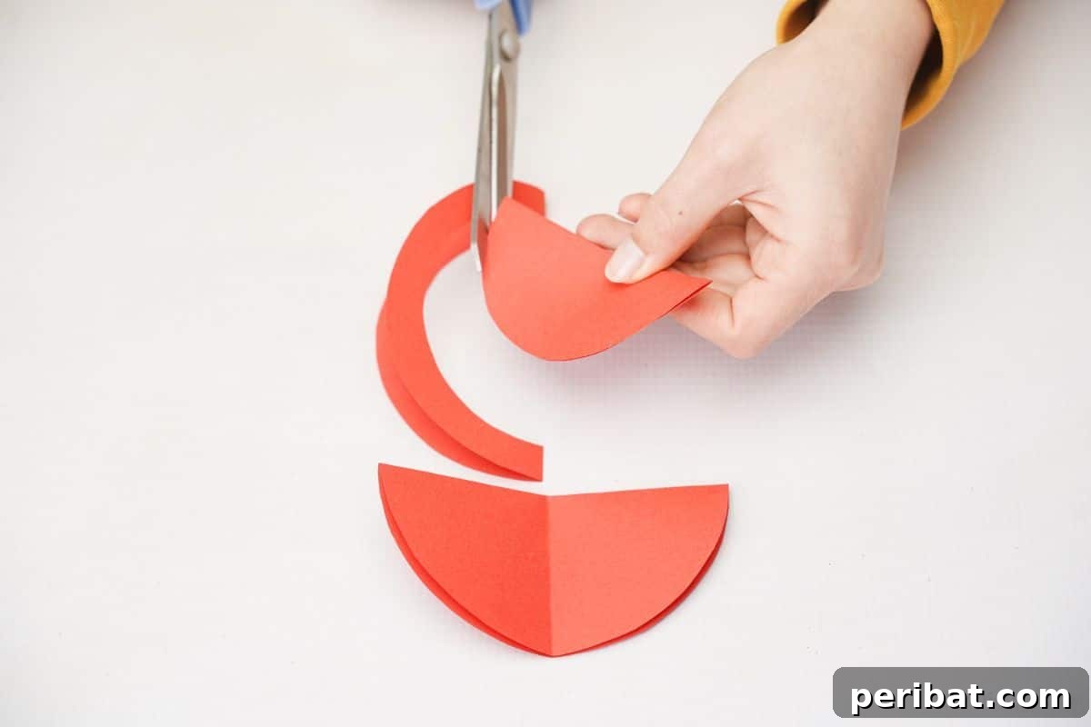 Scissors cutting a half-inch off the curved edge of a folded red paper circle.