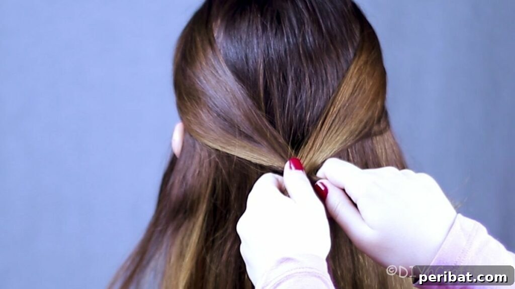 Effortless Chic Knotted Braid 6 Hands pulling sections of hair back to form the first knot