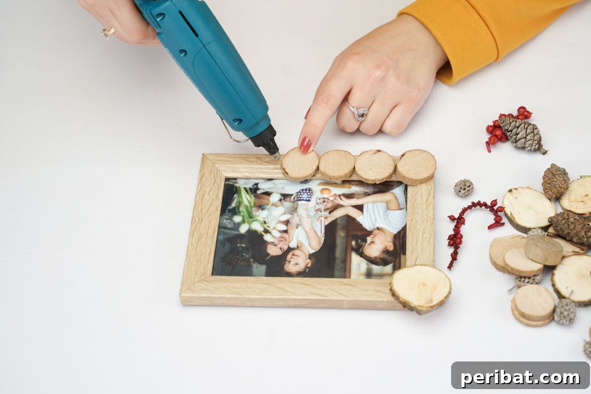 Tree Ring Photo Frame 3 hand using blue glue gun to add wood slices to frame
