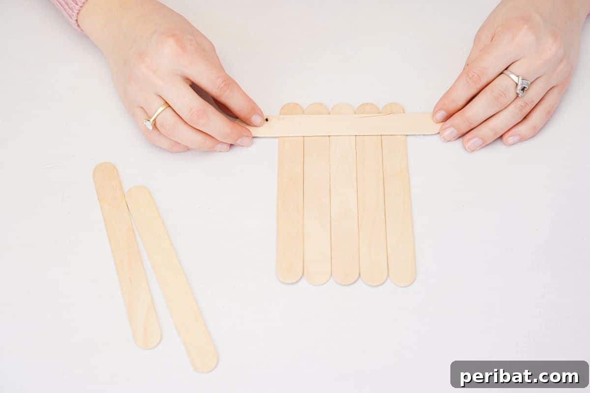 DIY Popsicle Stick Farmhouse Decor 2 hand placing craft sticks together on table
