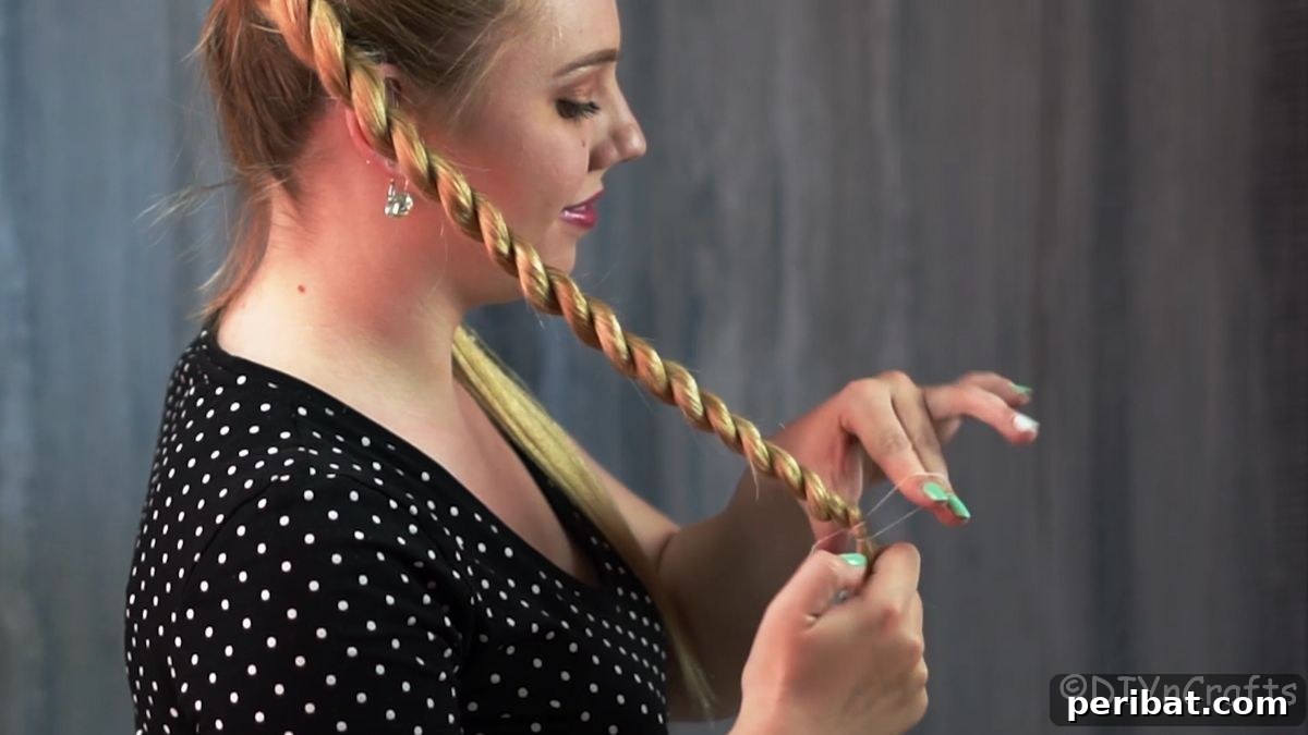 Stunning Braided Donut Bun Updo 9 Hand securing the end of a twisted braid with a small hair elastic.