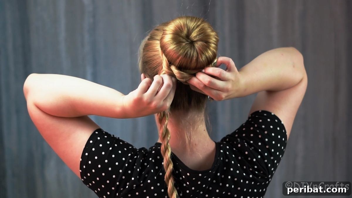 Stunning Braided Donut Bun Updo 13 Blonde woman wrapping a twisted braid around the base of her donut bun.