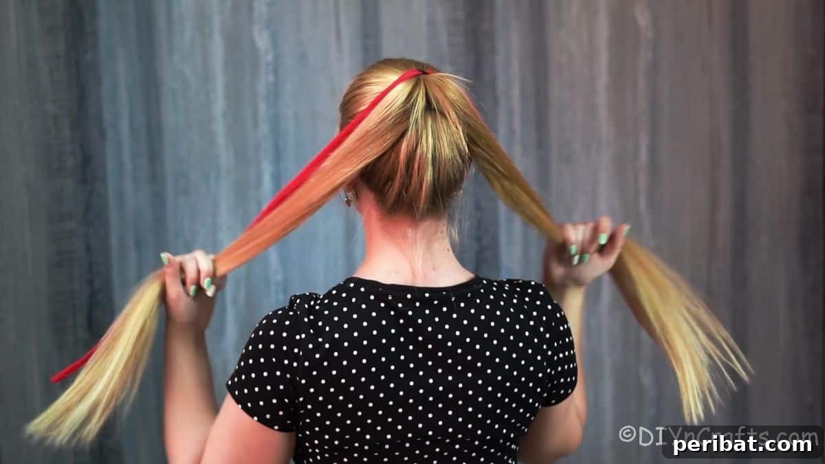 Twisted High Bun with Ribbon Accent 5 Hair from a high ponytail being divided into two sections, preparing for twisting with a ribbon to create the bun.