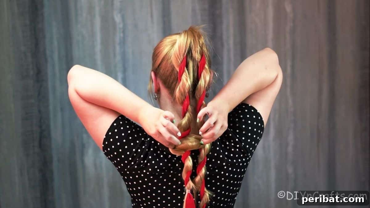 Twisted High Bun with Ribbon Accent 8 Blonde woman gently loosening her twisted hair sections to add volume and a softer look before forming the bun.