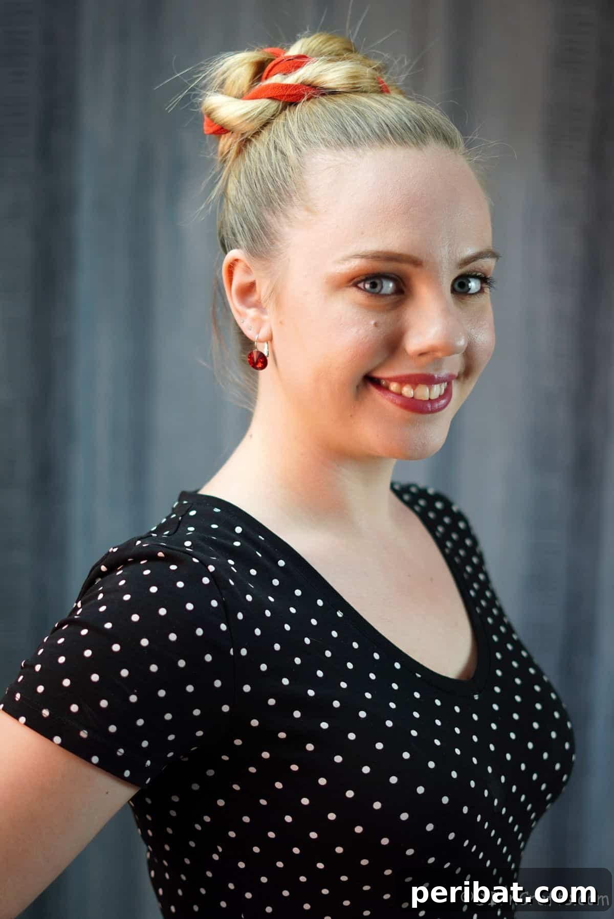 Twisted High Bun with Ribbon Accent 11 Final look of the elegant high twisted bun with red ribbon, showcasing a polished and stylish updo on a woman in a black shirt.